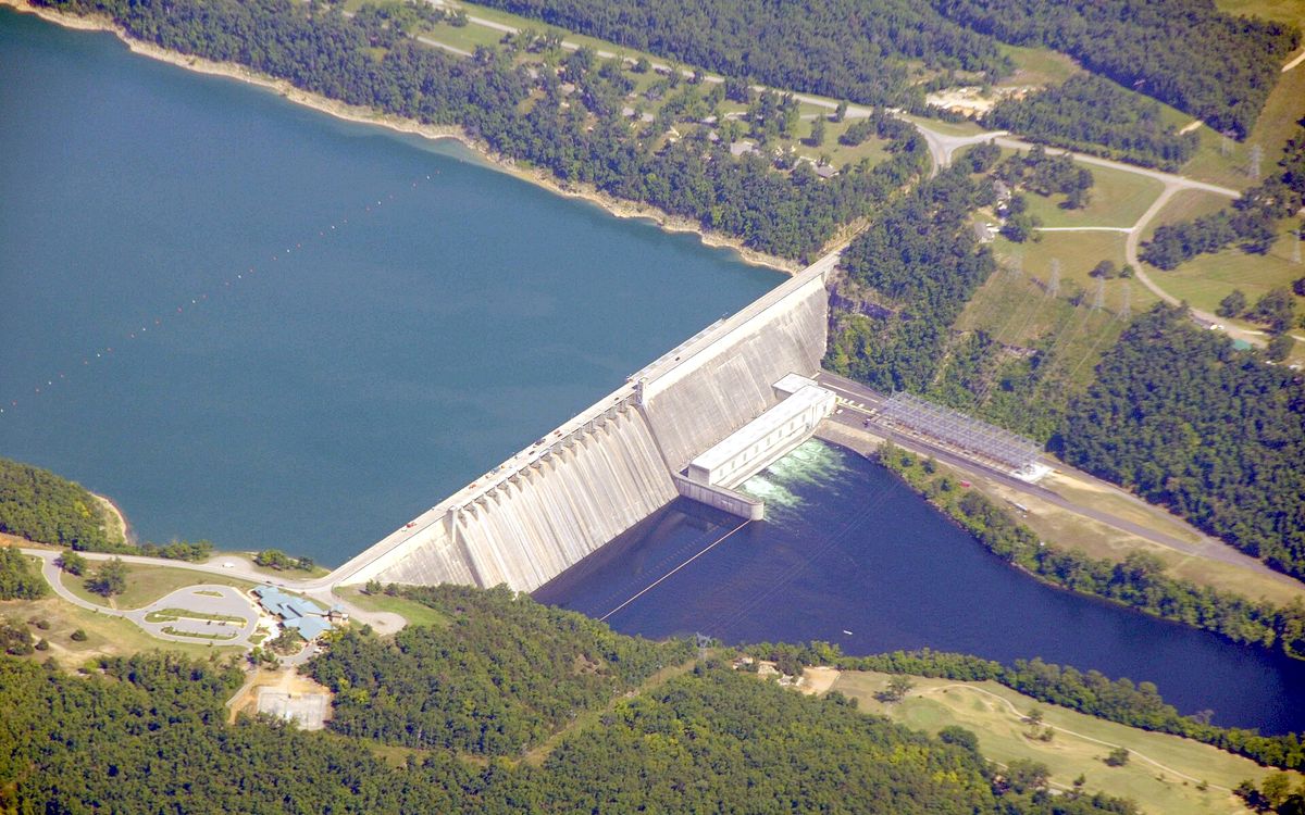 Aerial view of a concrete hydroelectric dam holding back a large reservoir