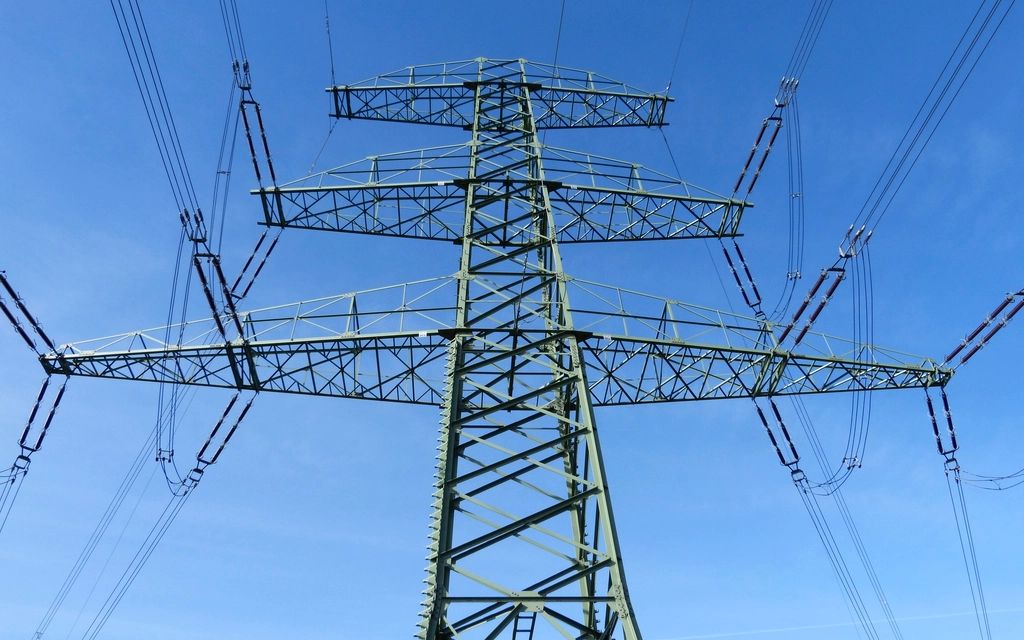 High voltage transmission tower with power lines against a blue sky